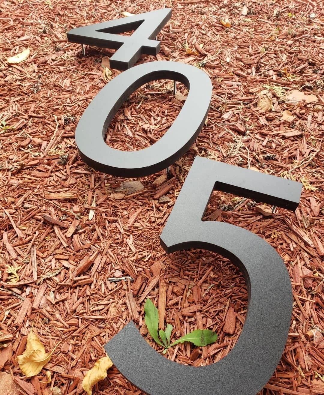 Metal address numbers arranged on a garden bed