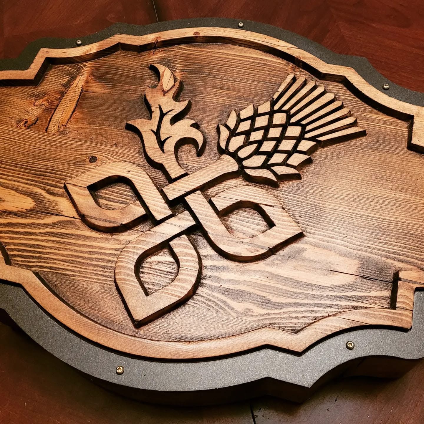 Carved wood pub sign with thistle artwork